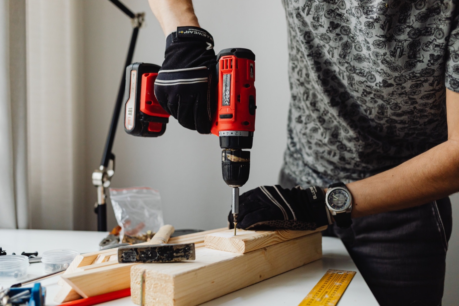 A tradesperson driving a screw into timber with a cordless drill